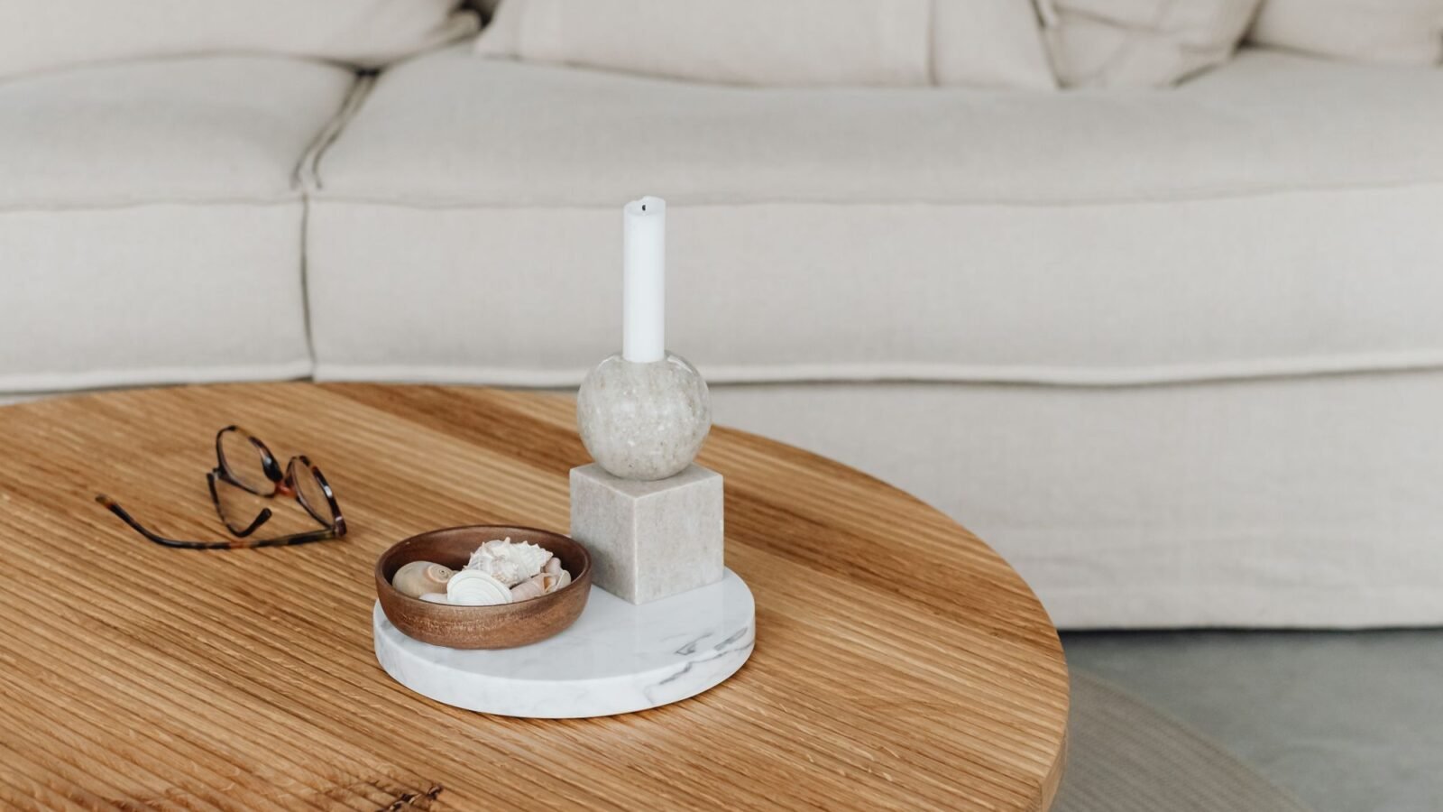 Cozy beige living room with a neutral sofa and round wooden coffee table.