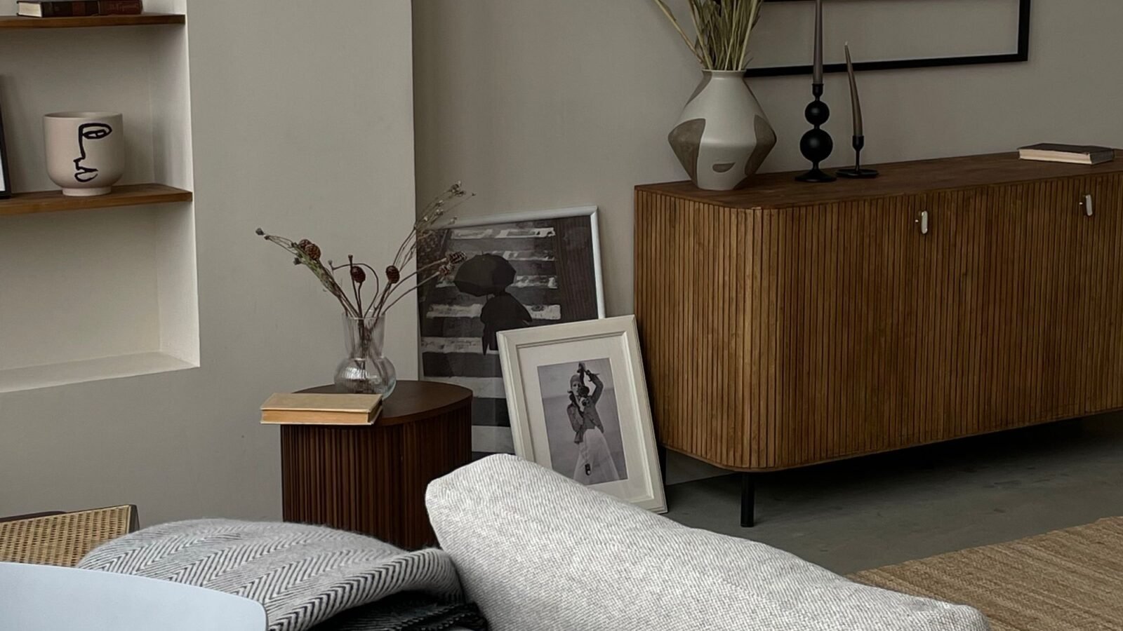 Neutral living room with a beige sofa, wood console, plants, and warm decor.