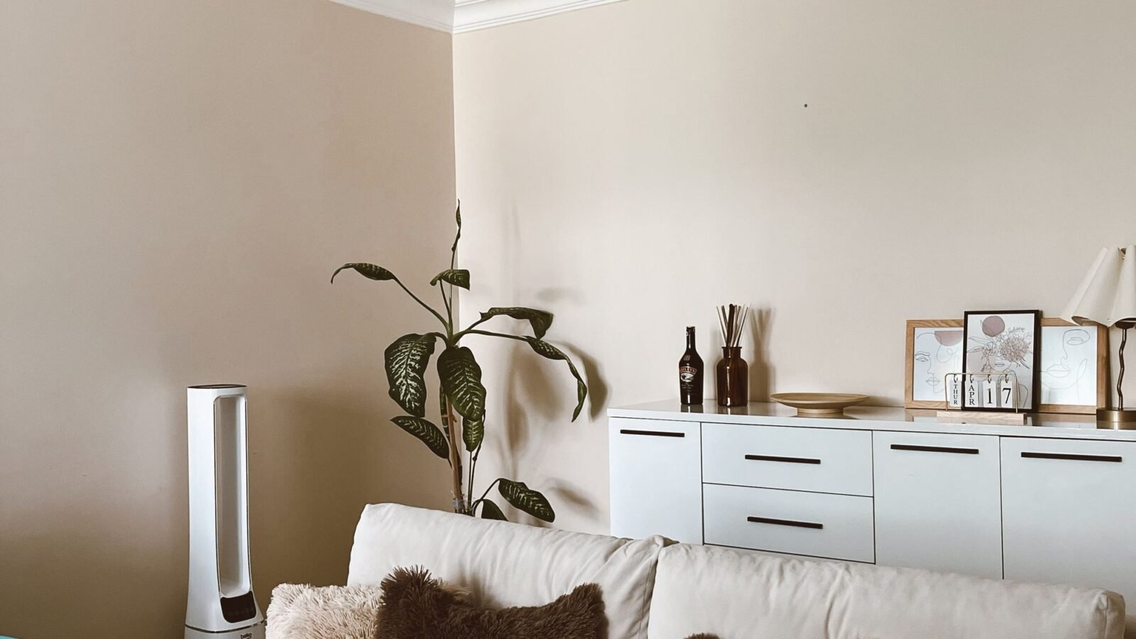 Warm cozy living room with neutral furniture, soft lighting, and simple decor.