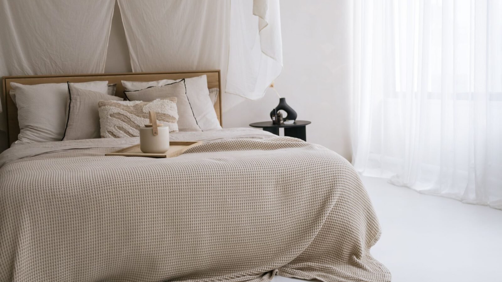 Cozy small bedroom with neutral bedding, soft natural light, and simple warm decor.