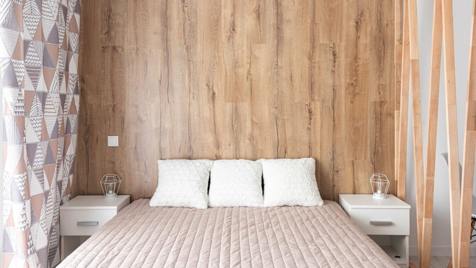 Contemporary bedroom with a wood accent wall, neutral bedding, and bedside lighting.