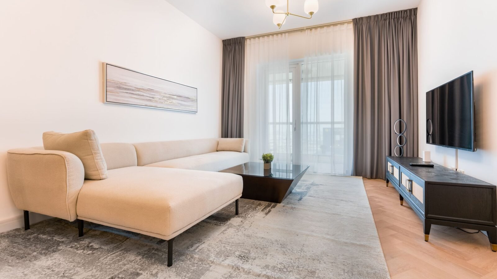 Small apartment living room with beige sofa, coffee table, rug, and compact TV area.