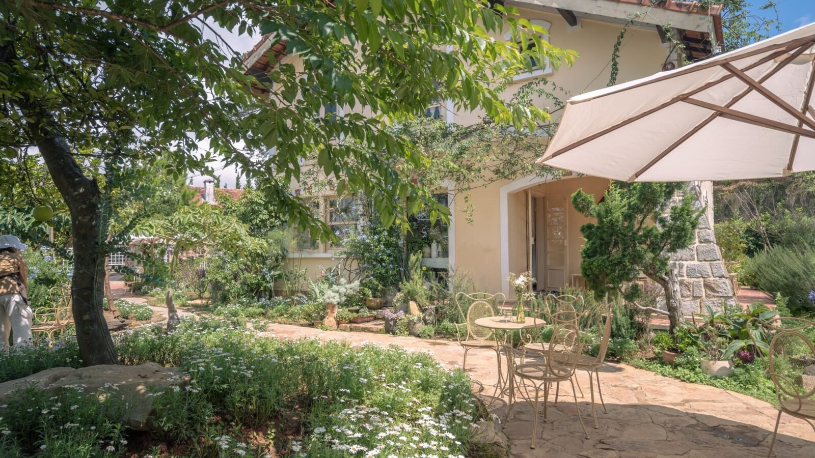 Small garden patio with seating, flowering plants, and lush greenery.