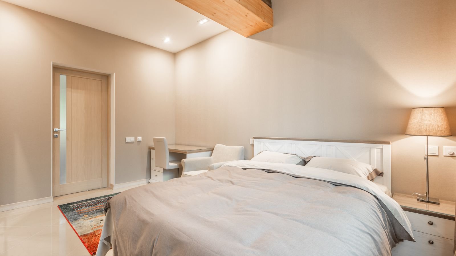 Bright bedroom with a bed and compact desk for a small workspace.