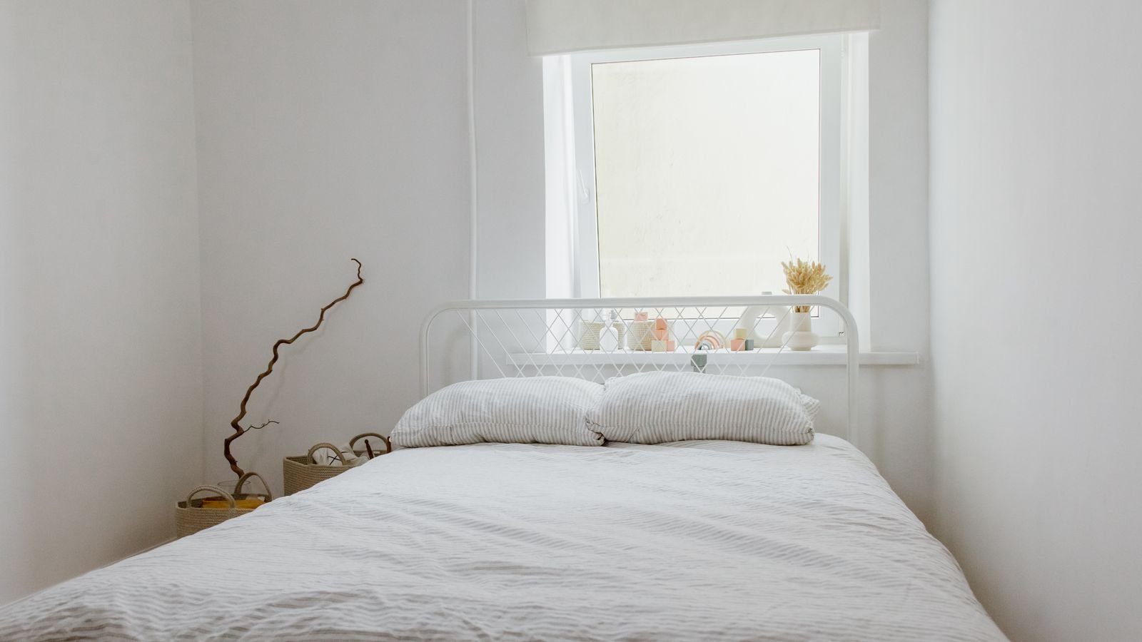 Bright small bedroom with white bedding, a window, and simple neutral decor.