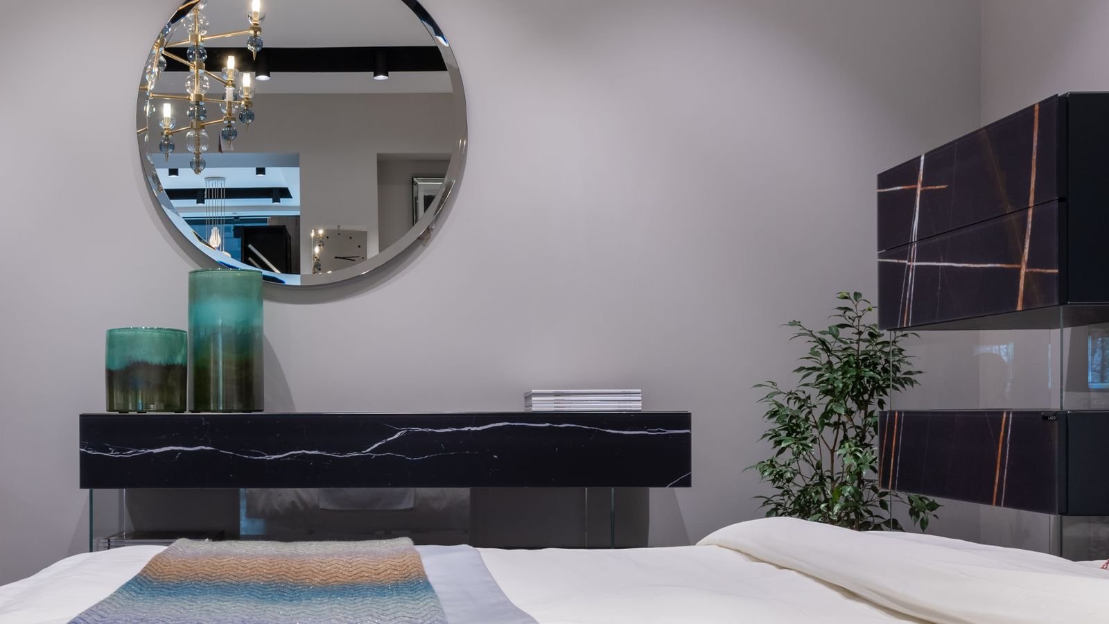 Neutral bedroom with a large round wall mirror creating a strong focal point.