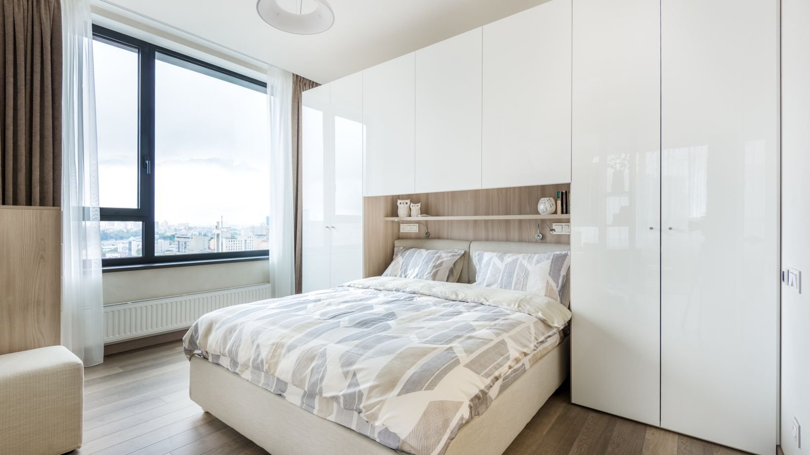Modern bedroom with a bed beside built-in wardrobe storage and shelving.