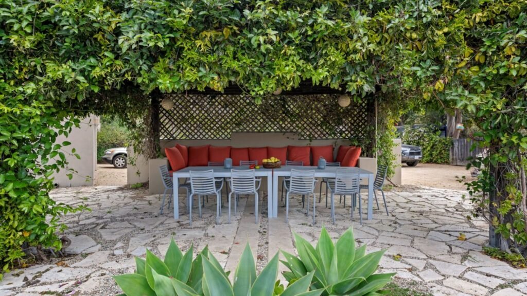 Cozy small patio with outdoor seating, table, vines, and lush greenery.