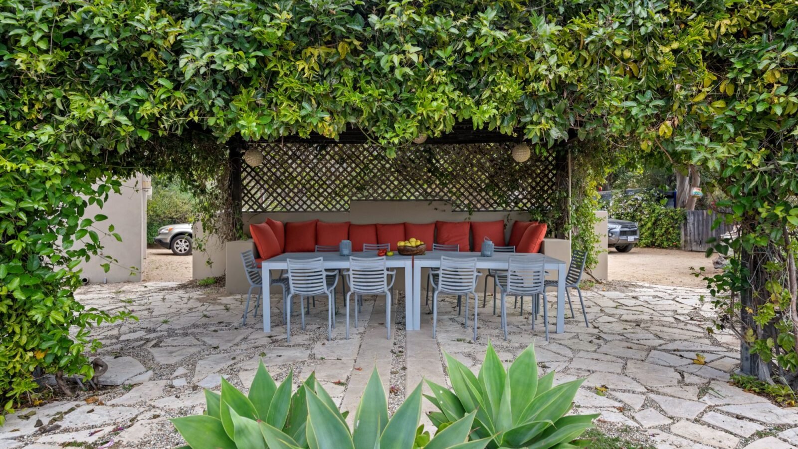 Cozy small patio with outdoor seating, table, vines, and lush greenery.