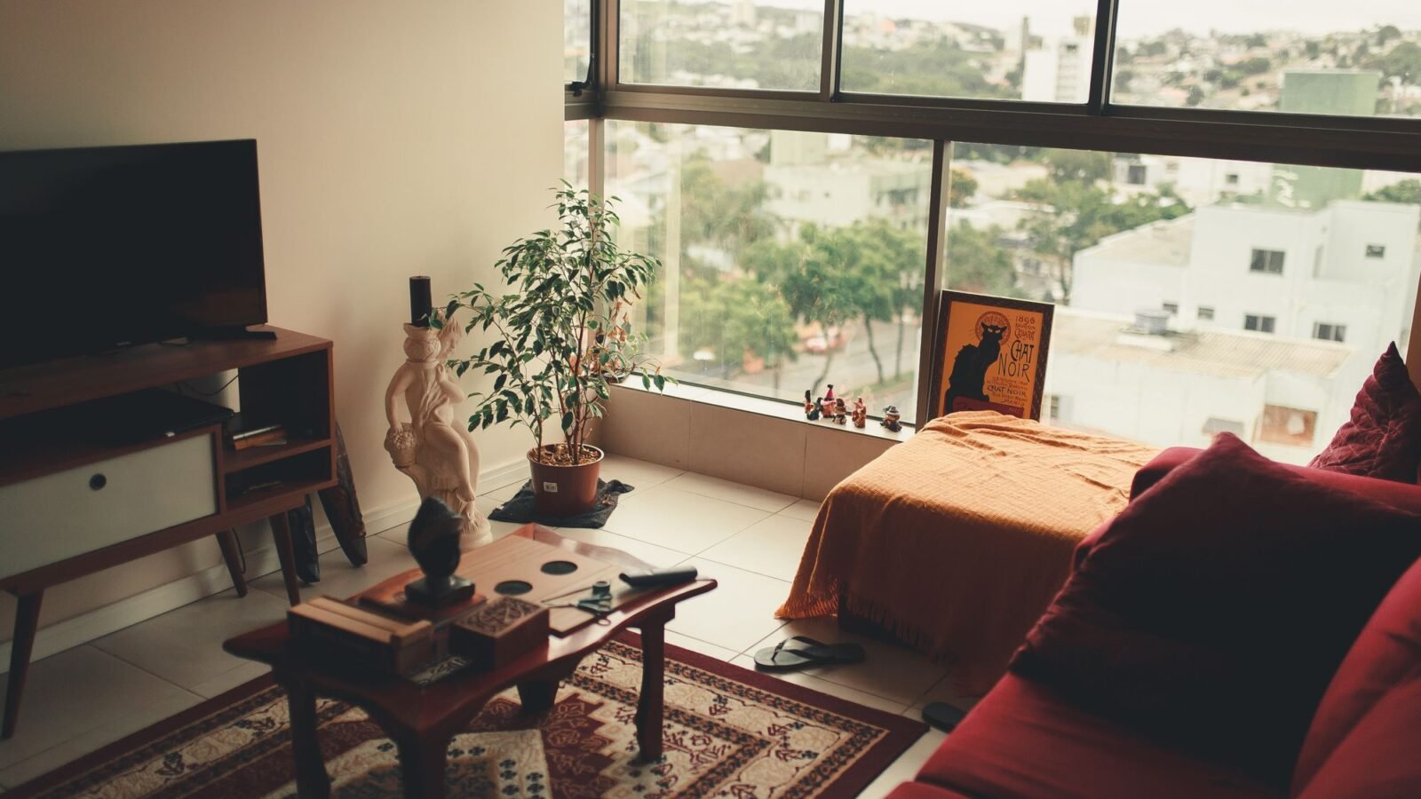 Small studio apartment with sofa and bed near a large window.