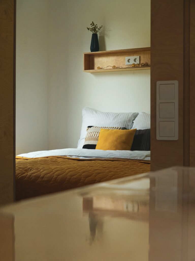 Calm neutral bedroom beside a window with soft natural daylight and light-toned bedding.