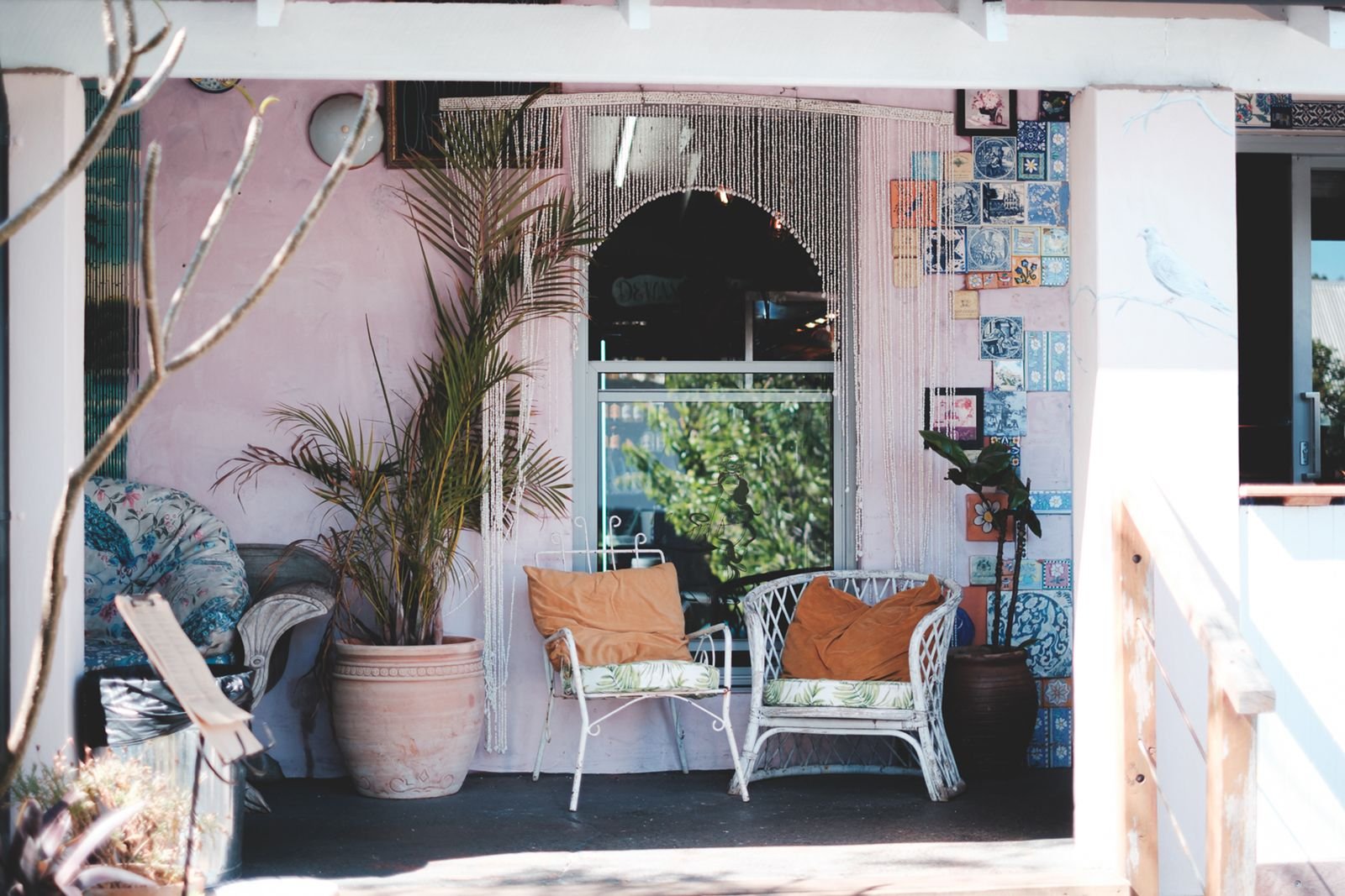 Cozy front porch with wicker chairs, cushions, and potted plants